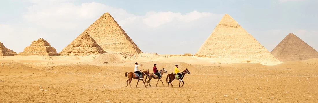 Panoramic view of great egyptian pyramids in giza and three riders in front of them